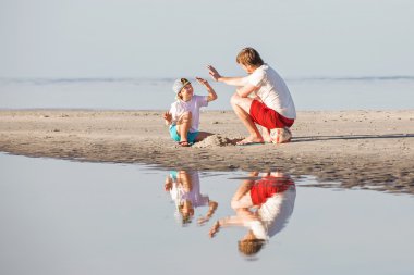 Mutlu baba ve oğul sahilde günbatımı ışığı iyi vakit geçiriyor