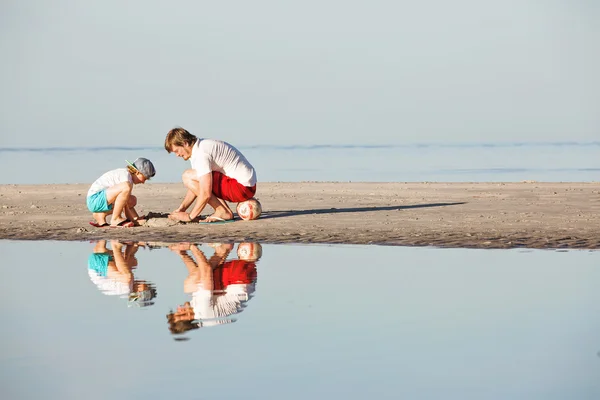 Happy father and son having great time on the beach in sunset light