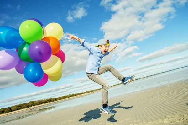 Mutlu çocuk renkli balonlarla sahilde çalış.