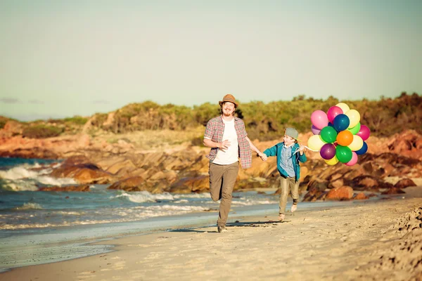 Feliz pai e filho se divertindo na praia ao pôr do sol — Fotografia de Stock