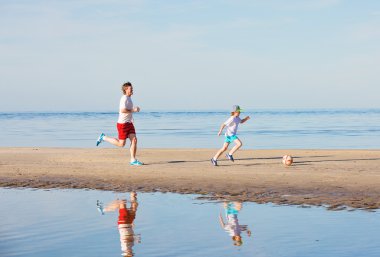 Mutlu baba ve oğul plaj futbol ya da futbol oynamak
