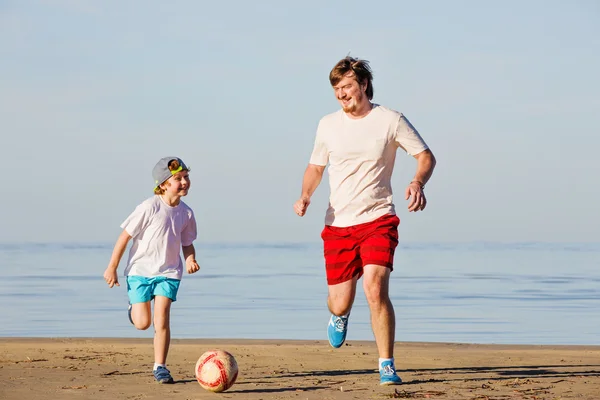 Lycklig far och son spela fotboll eller fotboll på stranden — Stockfoto