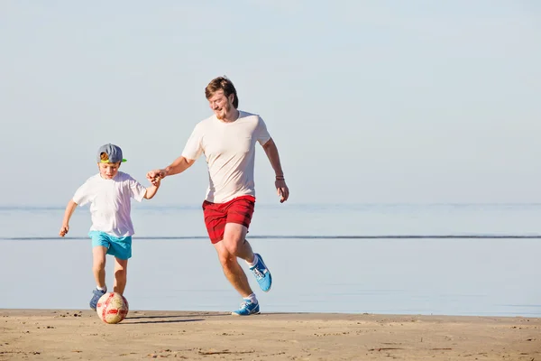 Lycklig far och son spela fotboll eller fotboll på stranden — Stockfoto