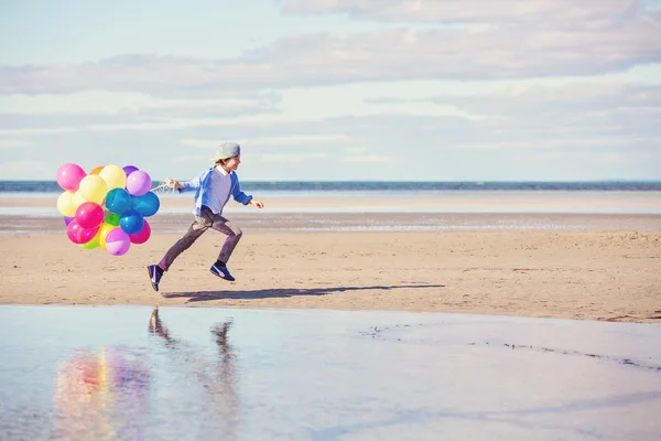 Szczęśliwy chłopiec bawi się kolorowe balony na plaży — Zdjęcie stockowe