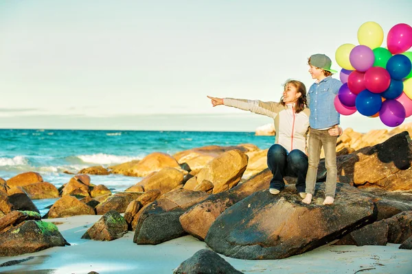 Bonne mère et son fils passer un bon moment sur la plage dans la lumière du coucher du soleil — Photo