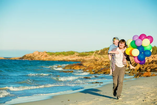 Feliz padre e hijo pasando un buen rato en la playa en la luz del atardecer — Foto de Stock