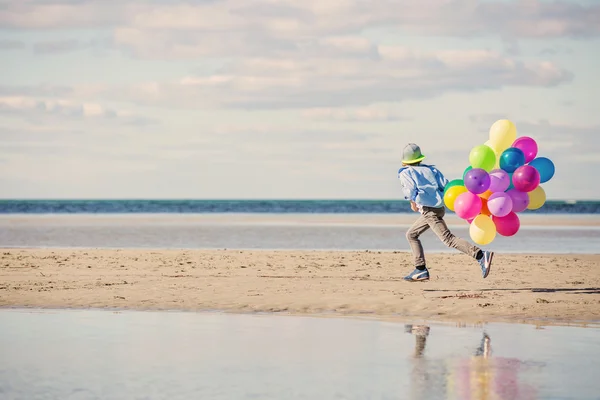 Happy boy plays with colored balloons on the beach — Stock Photo, Image