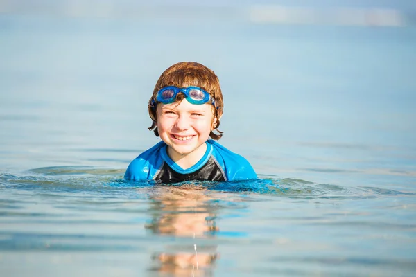 Happy smiling boy with goggles on swim in shallow water — 스톡 사진
