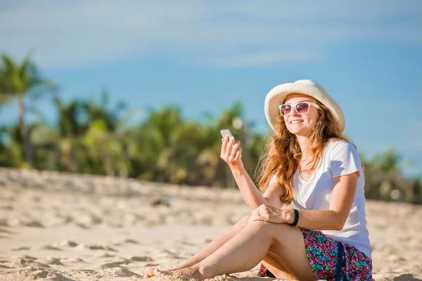 Красива молода жінка на пляжі в сонячний день з мобільним телефоном — стокове фото