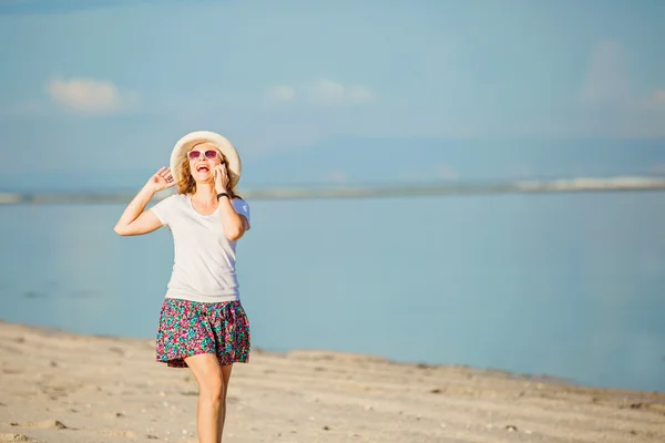 Beautiful young woman at the beach talking on mobile phone and laughing — Stockfoto