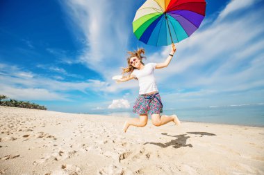 Gökkuşağı şemsiye plajda eğlenmek ile neşeli genç kız