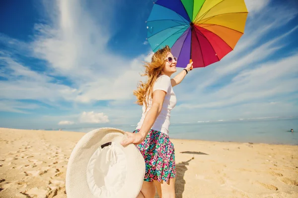 Jovencita alegre con paraguas de arco iris divertirse en la playa —  Fotos de Stock