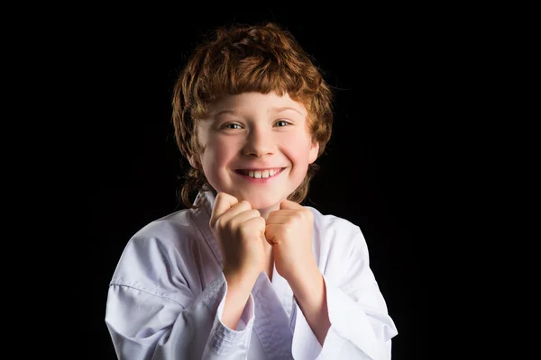 Karate çocuk izole siyah arka plan üzerine beyaz kimono içinde gülümseyen