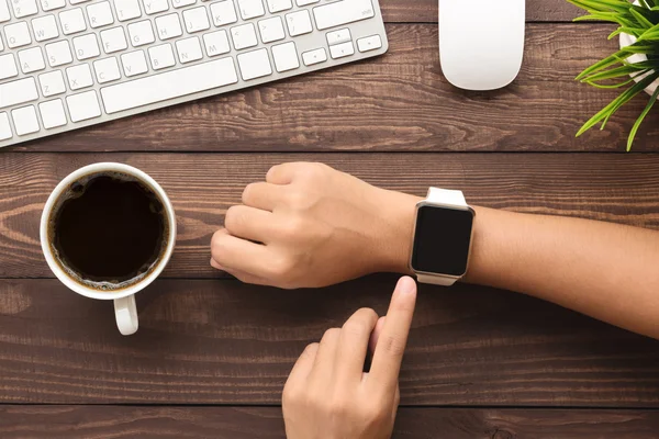 Main en utilisant smartwatch sur bureau vue dessus — Photo