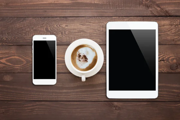 Tablet telefone branco e xícara de café na mesa de madeira vista superior — Fotografia de Stock