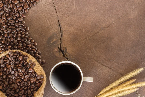 Šálek kávy a kávová zrna na pozadí dřeva — Stock fotografie