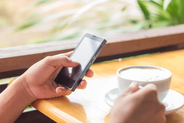 Cerca de mano utilizar el teléfono inteligente y beber café al aire libre —  Fotos de Stock
