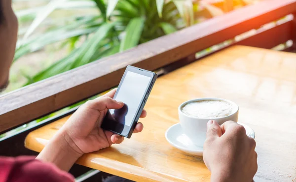 Man drink coffee and use smart phone in coffee shop at evening — Stok fotoğraf