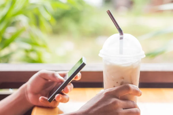 Hand houdt van koffie en slimme telefoon gebruiken — Stockfoto