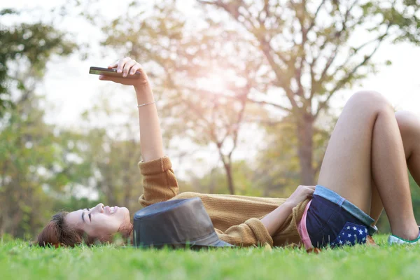 Молоді жінки посміхаються використовувати смартфон селфі на зеленій траві — стокове фото
