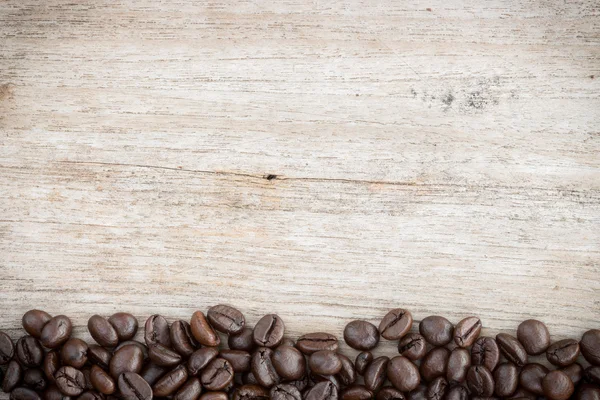Kávová zrna na zrno dřeva pozadí — Stock fotografie