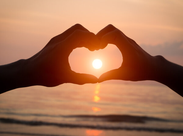 Couple holding hands heart love at sunset on the beach, valentine