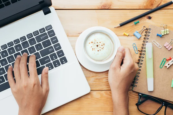 Mano de primer plano utilizando la computadora y la celebración de café en el lugar de trabajo — Foto de Stock