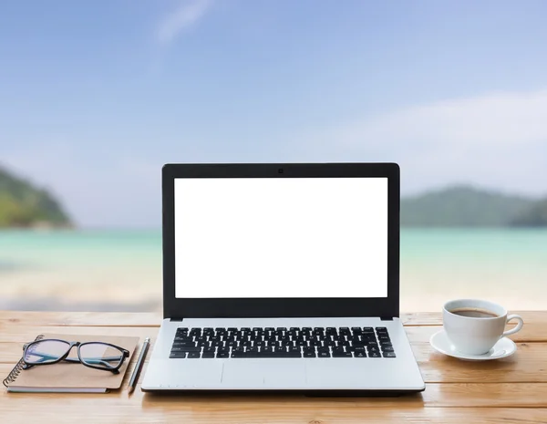 Computador portátil e café no espaço de trabalho de madeira e na praia — Fotografia de Stock
