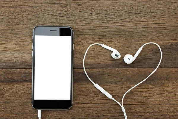 Phone white screen with headphone on wood table — Stock Photo, Image