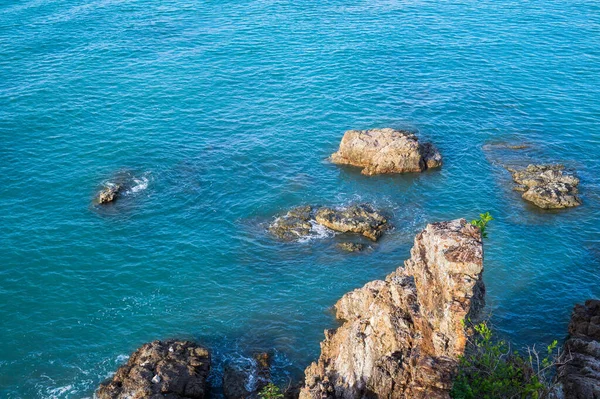 Top view from the cliff on the sea rocks and surf with waves. Beautiful blue water waves against rocky shore