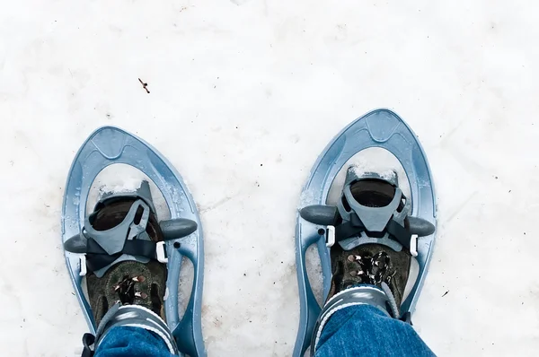 Nahaufnahme von Beinen mit blauer Jeans und Schneeschuhen — Stockfoto