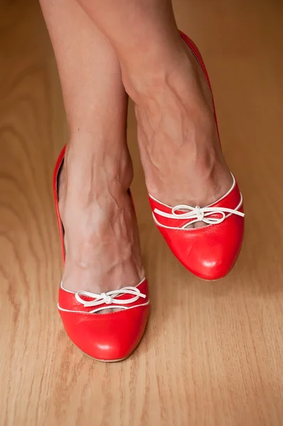 Close-up de mulher com sapatos vermelhos diferentes em parquet de madeira — Fotografia de Stock