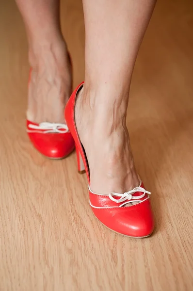 Close-up de mulher com sapatos vermelhos diferentes em parquet de madeira — Fotografia de Stock