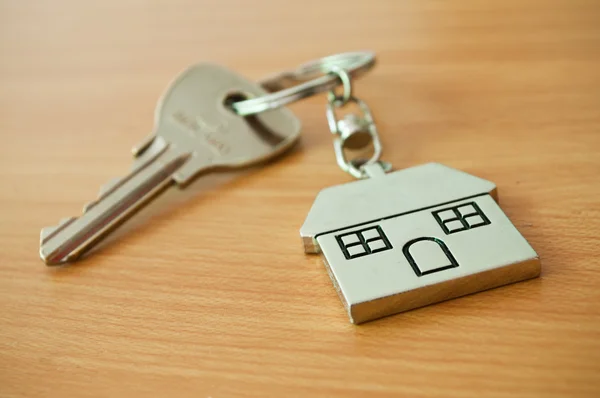 Metallschlüssel mit Schlüsselanhänger in Hausform auf Holzhintergrund — Stockfoto