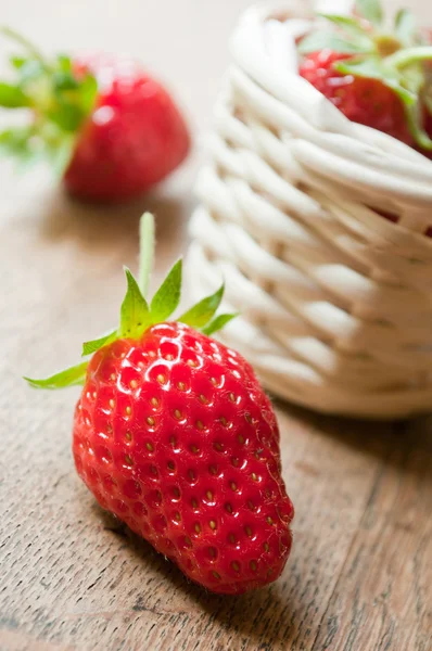 Closeup of strawberries in a wooden basket on wooden table background — Stock Photo, Image