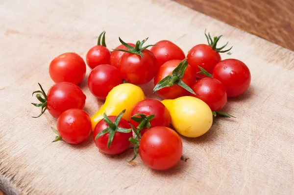 Tomates cereja em tábua de corte de madeira — Fotografia de Stock
