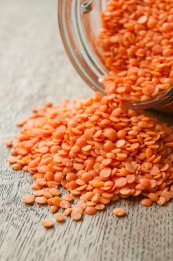 ahşap arka plan üzerinde cam kaba mercan mercimek düşme