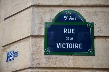 Taşlanmış binadaki geleneksel Paris sokak plakasının Victoire Caddesi 'ndeki Victory caddesine yakın plan.) 