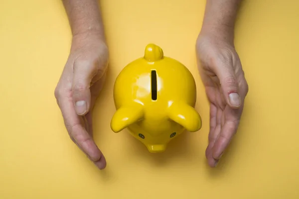 Fechar Mãos Homem Proteger Seu Banco Piggy Amarelo Fundo Amarelo — Fotografia de Stock