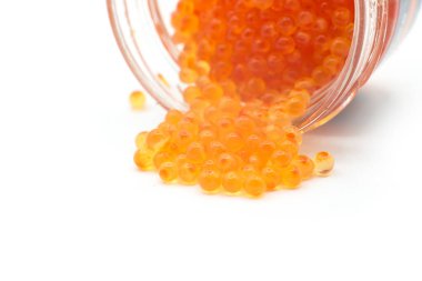 Beyaz arka planda cam bir kutudan düşen alabalık yumurtaları.