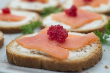 Aperatifleri kapatıyoruz. Beyaz tabakta somon ve peynirli tost.