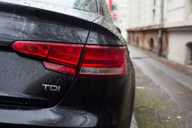 Mulhouse - Fransa - 12 Ocak 2021 - Sokağa park edilmiş siyah BMW TDI arabasının arka lambasına düşen yağmur damlaları 