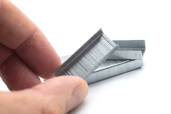 Closeup of staples pile in hand on white background