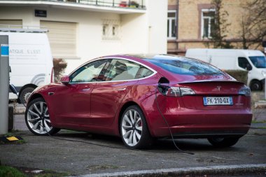 Strasbourg - Fransa - 4 Şubat 2021 - Sokakta şarj olan kırmızı testa arabaların arka görünümü, Tesla, ünlü Amerikan elektrikli arabalarıdır.