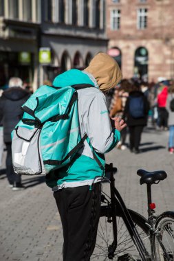 Strasbourg - Fransa - 13 Şubat 2021 Deleveroo yeleği ve sırt çantalı bir teslimatçının sokak bisikleti üzerindeki portresi