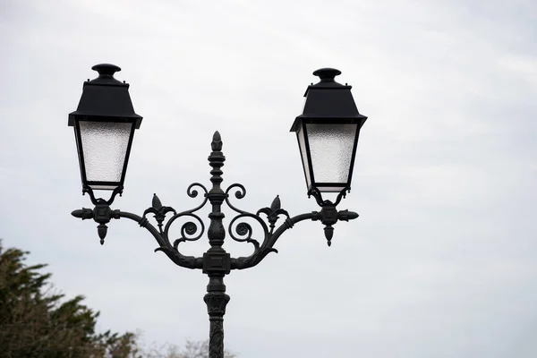 Closeup of two vintage street lights on cloudy sky background