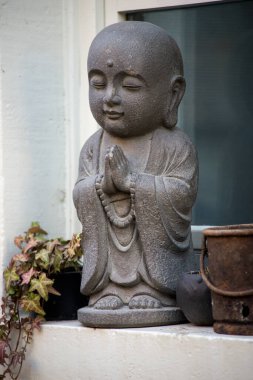 Caddedeki evin penceresinde kafası dumanlı küçük Buda 'nın yakın çekimi.