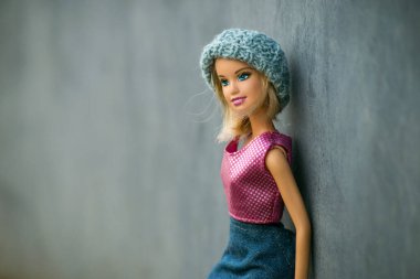 Mulhouse - Fransa - 12 Mart 2021 - Mavi kot etek giyen sarışın Barbie bebeğin portresi ve mavi duvar arkasında duran yün bir şapka