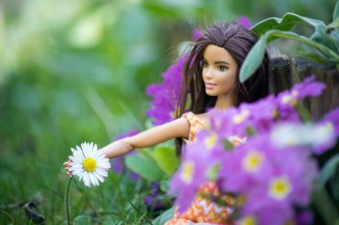 Mulhouse - Fransa - 31 Mart 2021 - Turuncu elbise giyen esmer Barbie bebek halk bahçesinde oturuyor