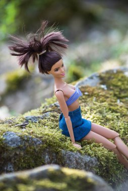  Mulhouse - Fransa - 2 Nisan 2021 - Ormanda oturan mavi kot etek ve bikini giyen Esmer Barbie bebeğin portresi